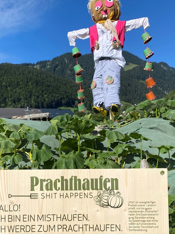 Von Kindern gebaute Vogelscheuchen dienen auf den Misthaufen als Blickfang und Schilder weisen auf das Projekt hin.